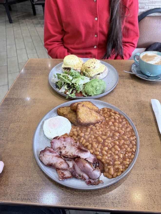 A breakfast plate and an avocado and poached egg salad with a cappuccino on a café table