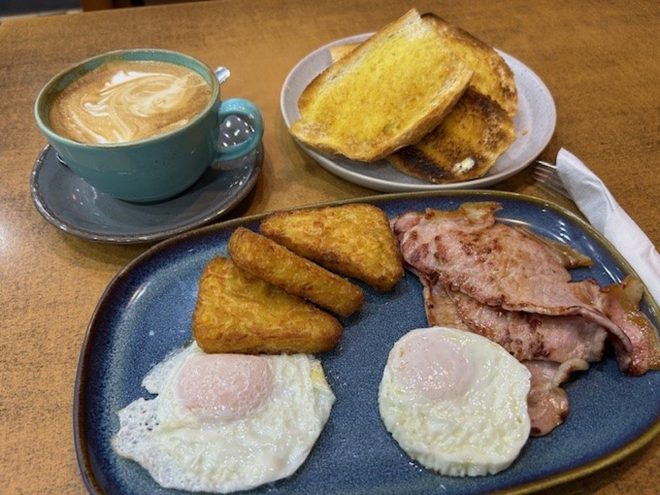 Bacon, hash browns and fried eggs with a latte and buttered toast