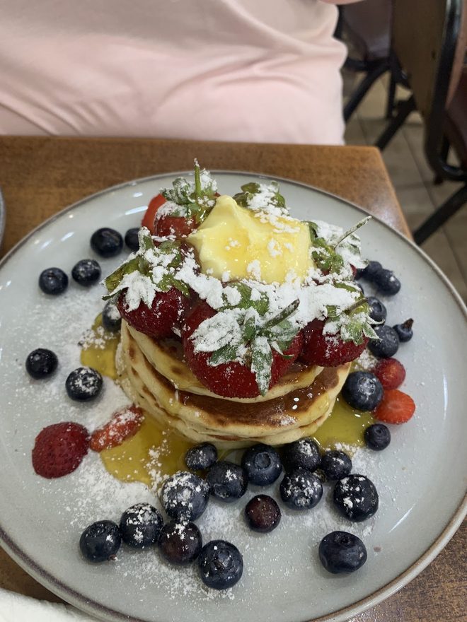 Pancakes with fresh fruit and cream on a white plate