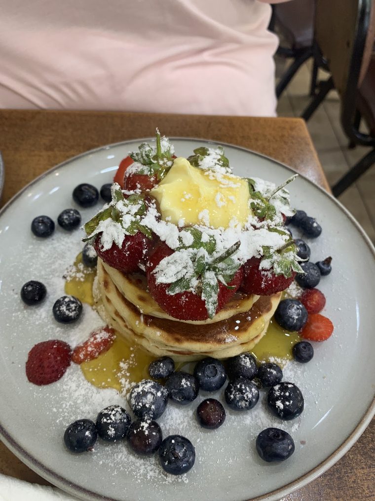 Pancakes topped with strawberries, blueberries, mango and cream