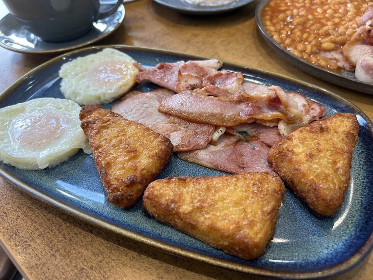 Hash browns, bacon and a fried egg on a blue speckled plate